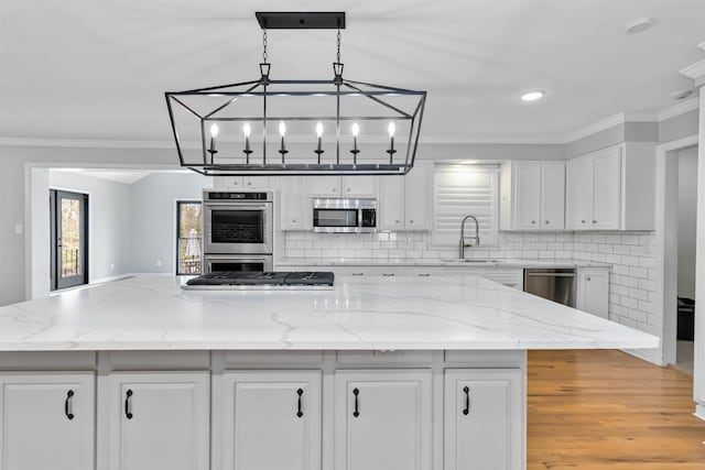 kitchen with white cabinets, a kitchen island, stainless steel appliances, and a sink