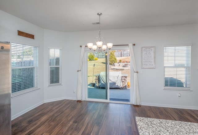 unfurnished dining area featuring a chandelier, dark wood-style flooring, visible vents, and baseboards