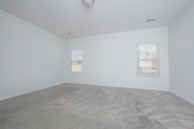 carpeted empty room with plenty of natural light, visible vents, and baseboards