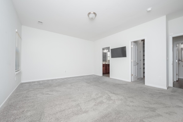 unfurnished bedroom featuring carpet, connected bathroom, visible vents, and baseboards