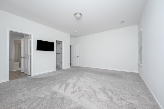 unfurnished bedroom with carpet floors, baseboards, visible vents, and a walk in closet