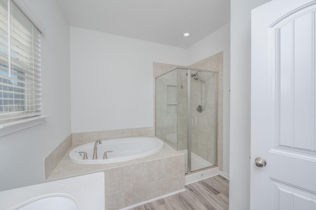 bathroom featuring a shower stall, a bath, and wood finished floors