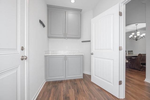 interior space featuring a notable chandelier, dark wood-style flooring, and baseboards