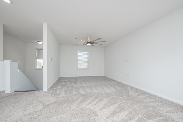 empty room featuring light carpet, ceiling fan, and baseboards