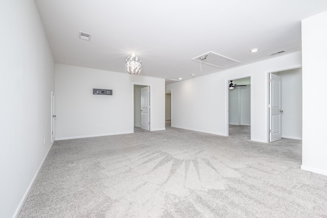 carpeted spare room with baseboards, visible vents, and attic access