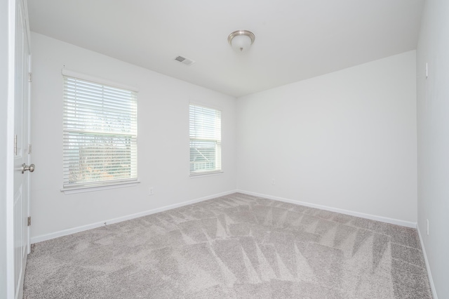 empty room with baseboards, visible vents, and carpet flooring