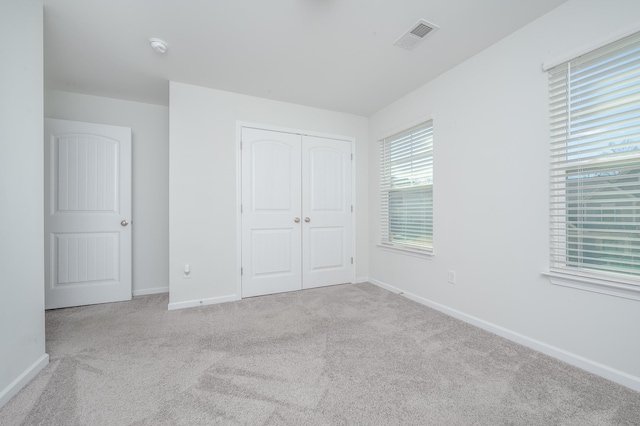 unfurnished bedroom featuring a closet, carpet flooring, visible vents, and baseboards