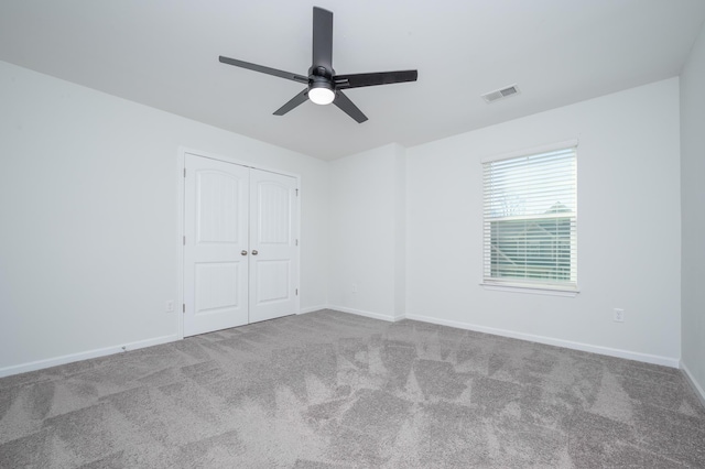 empty room with a ceiling fan, carpet flooring, visible vents, and baseboards