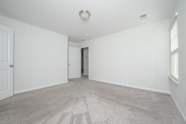 carpeted empty room featuring a healthy amount of sunlight, baseboards, and visible vents