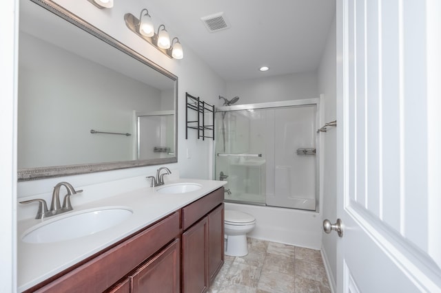 bathroom with double vanity, shower / bath combination with glass door, a sink, and visible vents