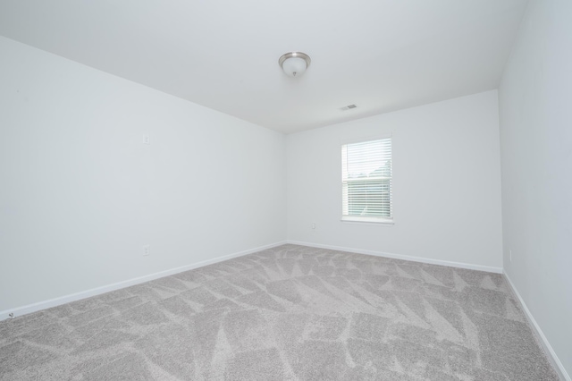 empty room featuring carpet floors, visible vents, and baseboards