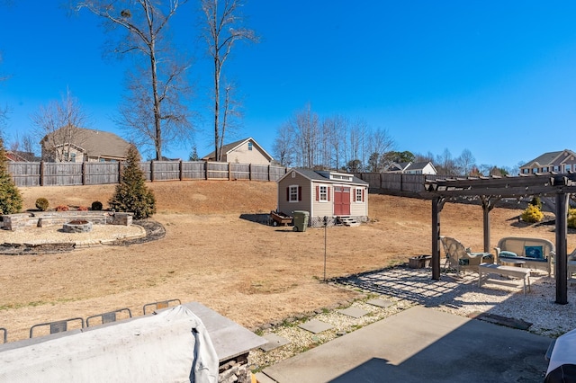 view of yard featuring an outdoor fire pit, a fenced backyard, an outbuilding, and a pergola