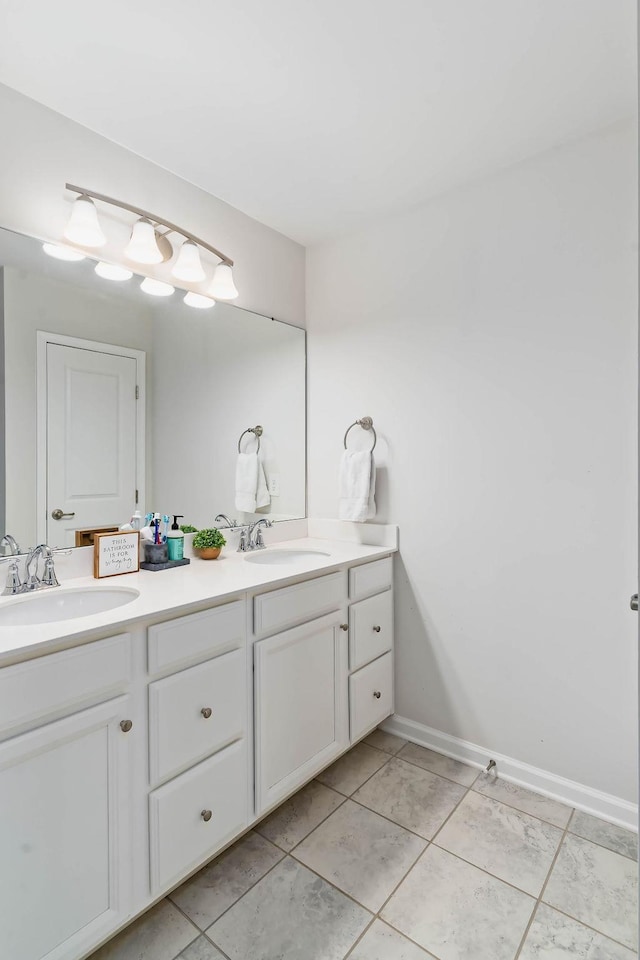 bathroom with double vanity, a sink, and baseboards