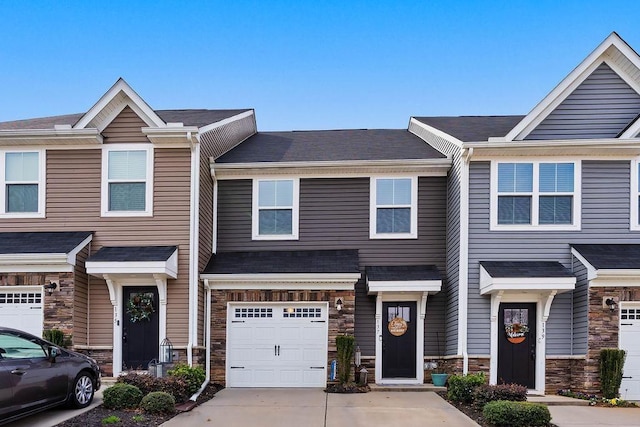 townhome / multi-family property featuring a garage, stone siding, roof with shingles, and concrete driveway