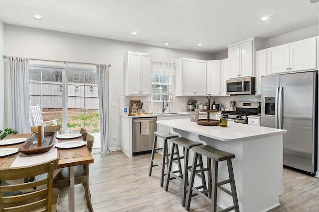 kitchen featuring decorative backsplash, a center island, stainless steel appliances, light countertops, and white cabinetry