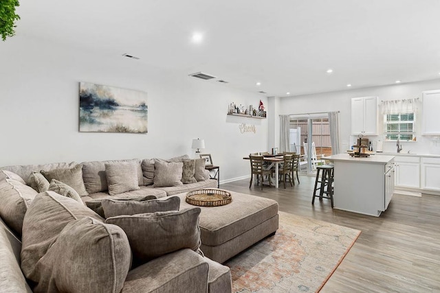 living room featuring baseboards, light wood finished floors, visible vents, and recessed lighting