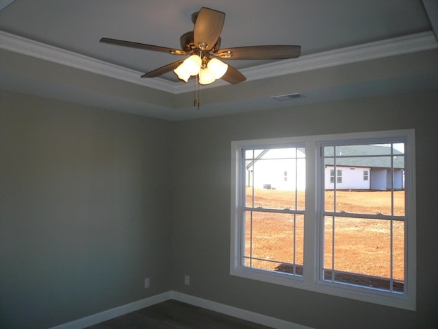 empty room with visible vents, baseboards, ceiling fan, a tray ceiling, and crown molding