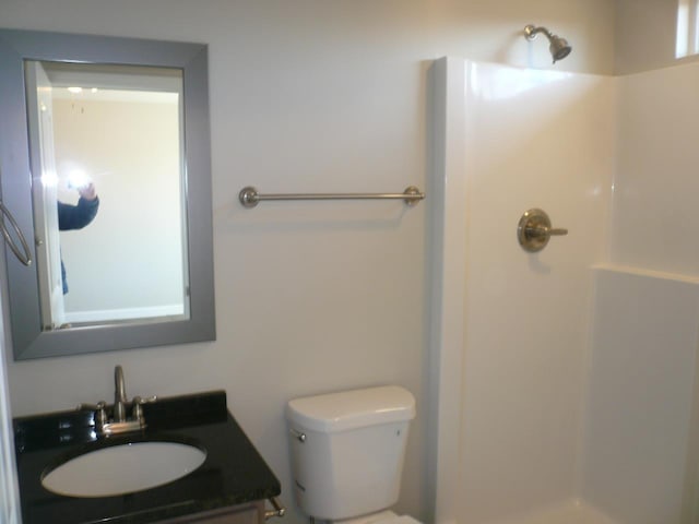 bathroom featuring a shower, vanity, and toilet