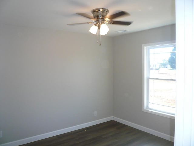 empty room with a healthy amount of sunlight, dark wood-style floors, ceiling fan, and baseboards