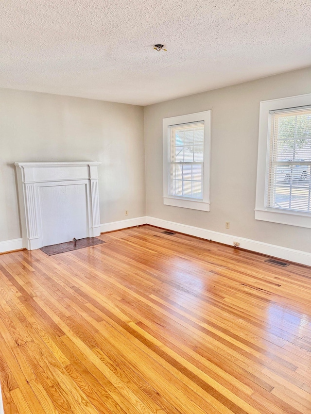 unfurnished room featuring light wood-type flooring, visible vents, and baseboards