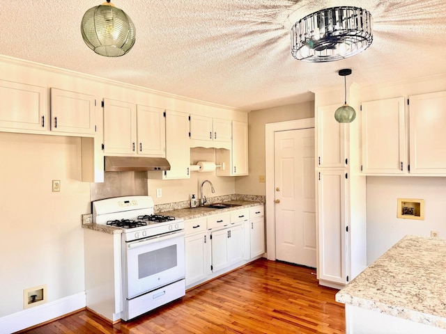 kitchen with white gas stove, light wood finished floors, a sink, and under cabinet range hood