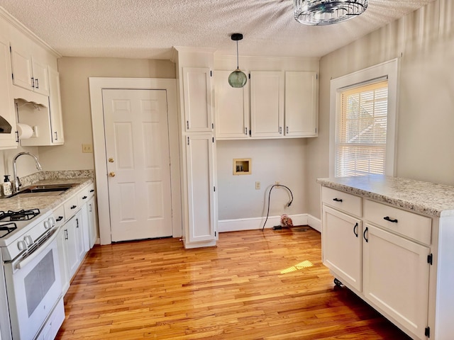 kitchen with light wood-type flooring, white gas range, a sink, and white cabinetry