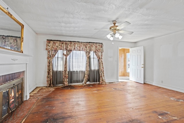 unfurnished living room with a brick fireplace, wood-type flooring, baseboards, and a ceiling fan