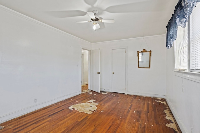 unfurnished bedroom featuring ornamental molding, a ceiling fan, baseboards, and hardwood / wood-style flooring