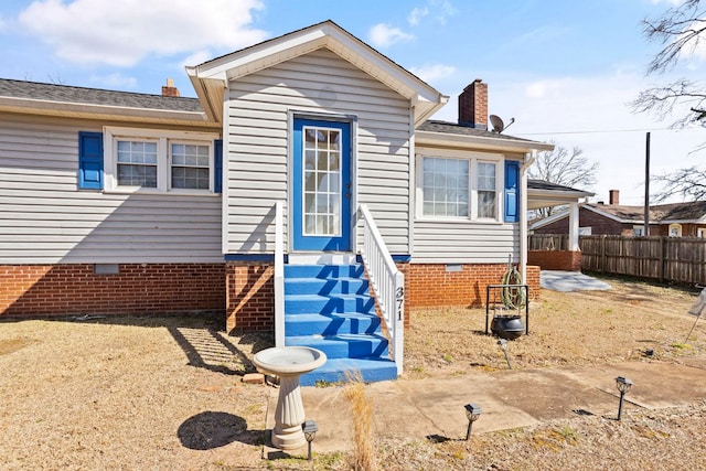 rear view of property featuring crawl space, a chimney, and fence