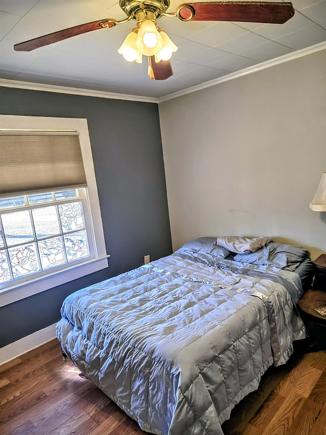 bedroom featuring ceiling fan, ornamental molding, and wood finished floors