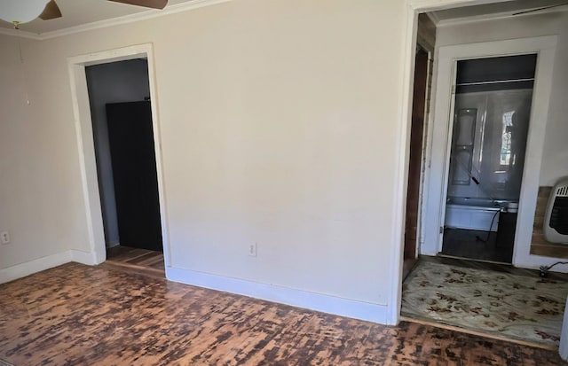 unfurnished room with heating unit, ornamental molding, ceiling fan, wood finished floors, and baseboards