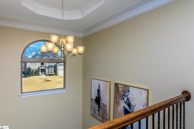 interior space with a tray ceiling, a chandelier, and ornamental molding