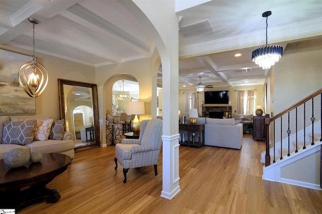 living room featuring light wood finished floors, a fireplace, coffered ceiling, and visible vents