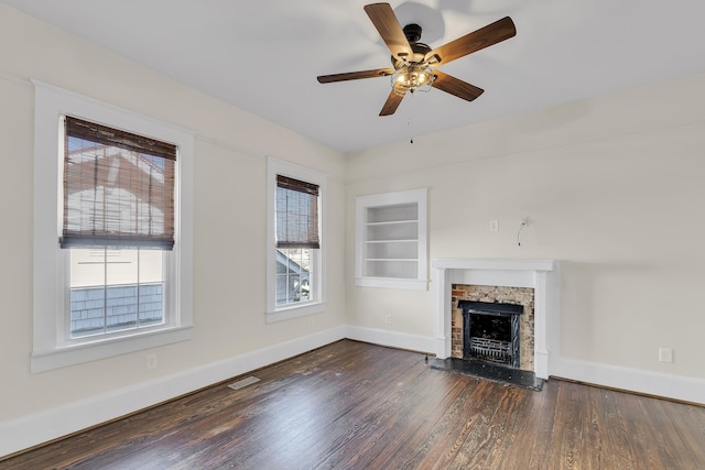 unfurnished living room featuring built in shelves, a fireplace, baseboards, and wood finished floors