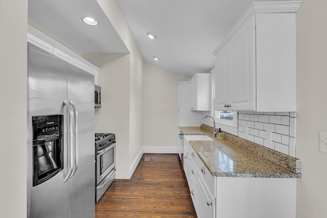 kitchen featuring stainless steel appliances, tasteful backsplash, white cabinets, vaulted ceiling, and light stone countertops