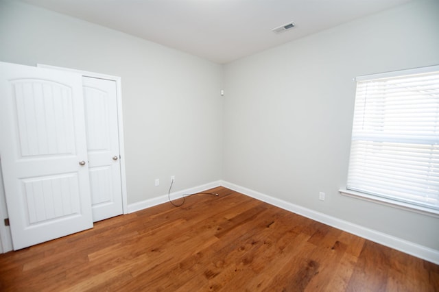 unfurnished bedroom featuring baseboards, visible vents, and wood finished floors