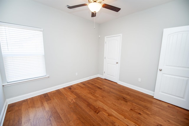 spare room featuring wood finished floors, a ceiling fan, and baseboards