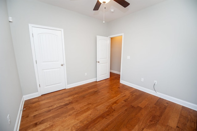 unfurnished bedroom featuring ceiling fan, baseboards, and wood finished floors