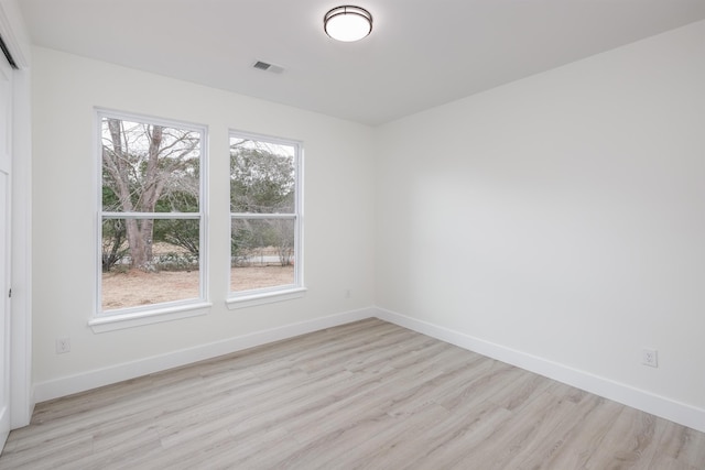 empty room with light wood-type flooring, visible vents, and baseboards