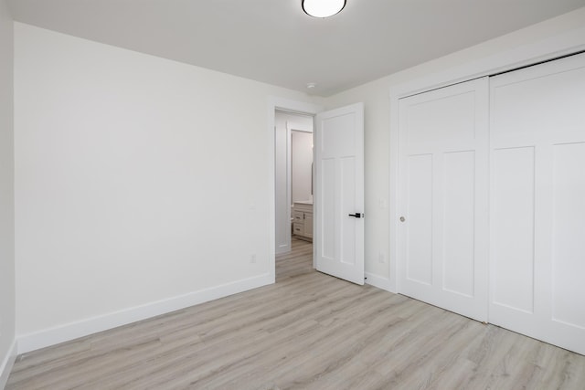 unfurnished bedroom with a closet, wood finished floors, and baseboards