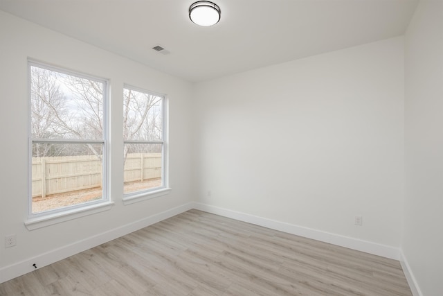 spare room with light wood-style floors, visible vents, and baseboards