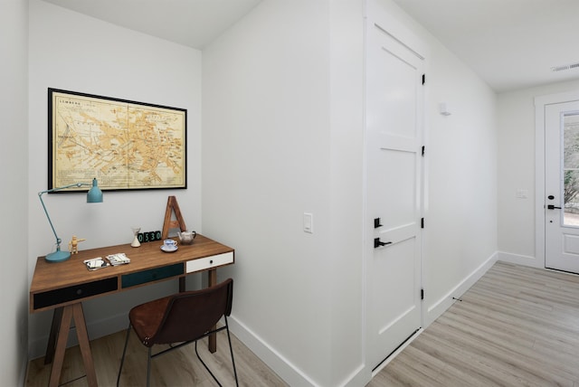 office area with light wood-type flooring, visible vents, and baseboards