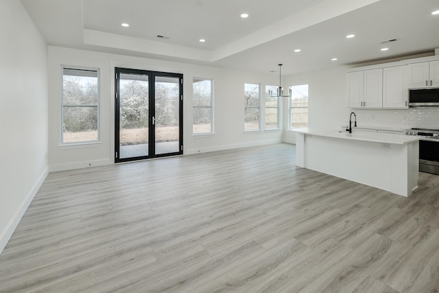 kitchen with a tray ceiling, french doors, stainless steel appliances, backsplash, and open floor plan