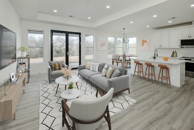 living area with french doors, recessed lighting, a raised ceiling, visible vents, and light wood-style flooring