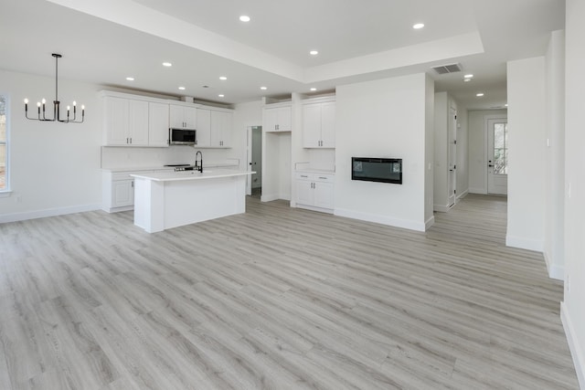 kitchen with white cabinets, a glass covered fireplace, stainless steel microwave, light countertops, and recessed lighting