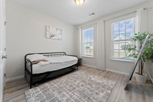 bedroom featuring light wood-type flooring, baseboards, multiple windows, and visible vents