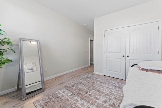 bedroom featuring a closet, light wood-style flooring, and baseboards