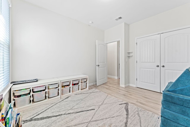 bedroom featuring a closet, wood finished floors, visible vents, and baseboards