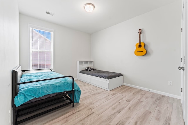 bedroom featuring visible vents, baseboards, and wood finished floors