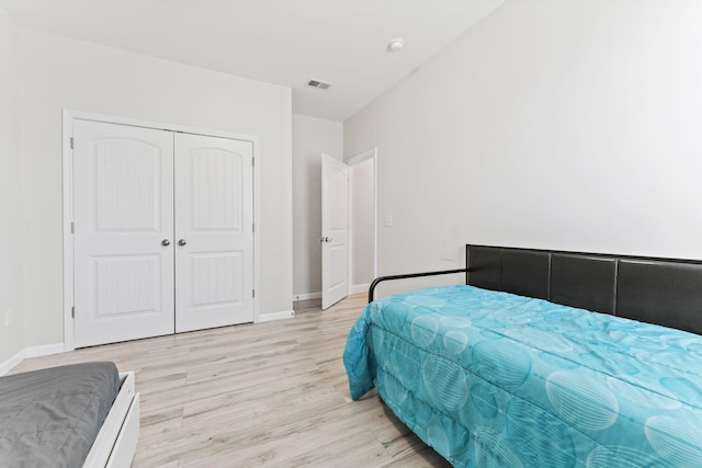 bedroom with light wood-style flooring, a closet, visible vents, and baseboards